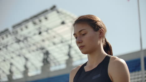 Beautiful-woman-athlete-at-the-stadium-breathing-and-preparing-to-start-the-race.-Motivation-and-tuning-for-the-race.-Concentration-and-attitude